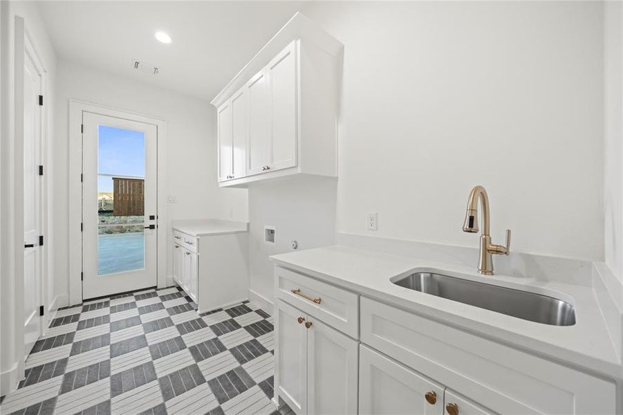 Utility room featuring white cabinetry, light-toned countertops, and a stainless steel undermount sink with a gold-tone faucet