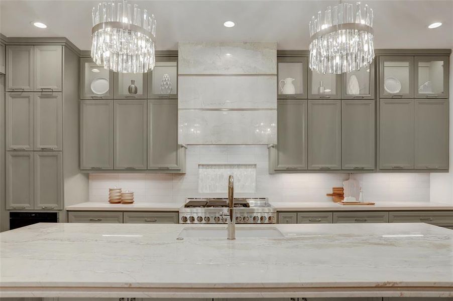 Unique design details, including Stone vent hood with polished nickel accents, iridescent picket tile in niche behind stainless steel 48 inch range, both undercabinet lighting and LED glass cabinets above.