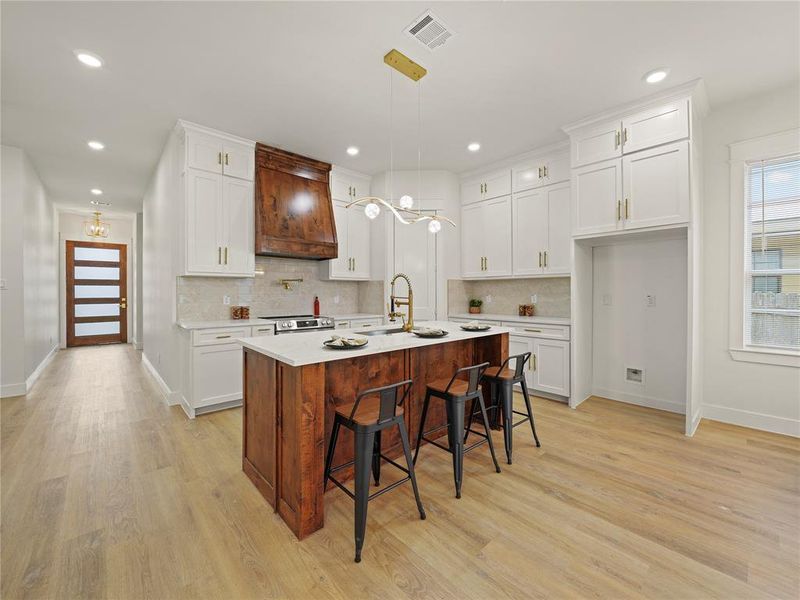 Kitchen featuring a breakfast bar, white cabinetry, light stone countertops, and light wood-style flooring