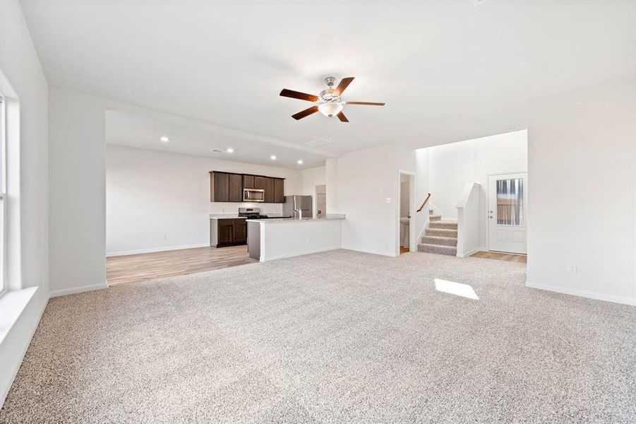 Unfurnished living room featuring light carpet and ceiling fan