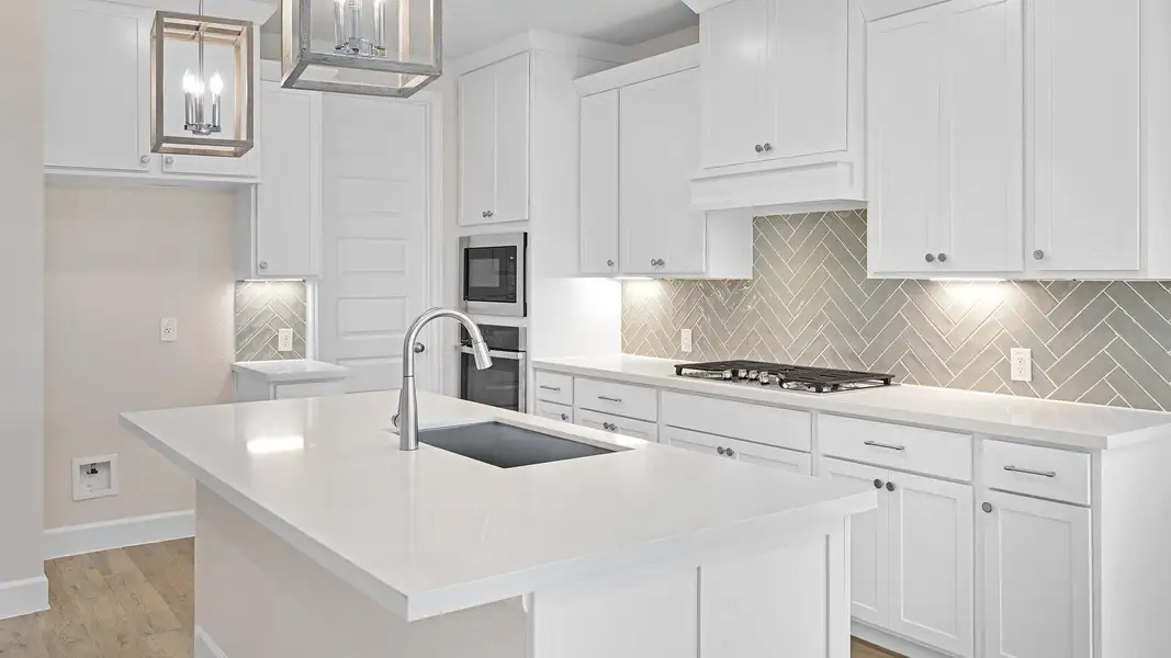 Kitchen with hanging light fixtures, a kitchen island with sink, tasteful backsplash, white cabinetry, and stainless steel appliances