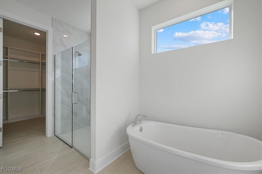 Full bathroom with a soaking tub, a marble finish shower, and a walk in closet