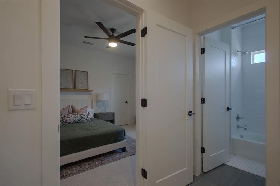 Tiled bedroom featuring ceiling fan and ensuite bathroom