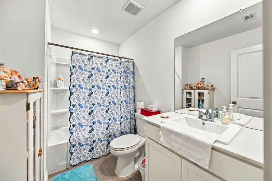 Bright and inviting bathroom featuring a modern vanity with ample storage, a stylish blue floral shower curtain, and sleek fixtures, creating a cozy and functional space.