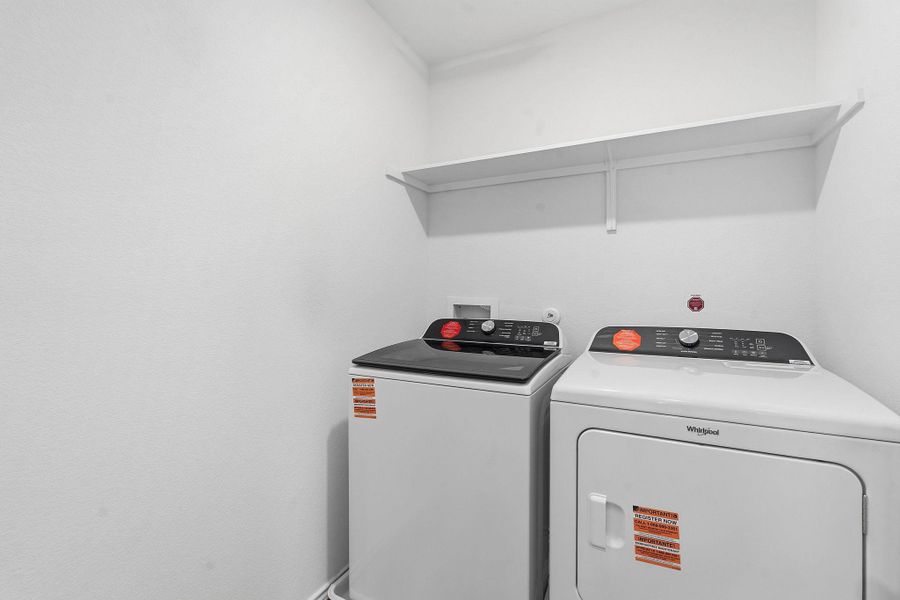 Dedicated laundry area featuring a white washer and dryer set, a wall-mounted storage shelf, and white painted walls