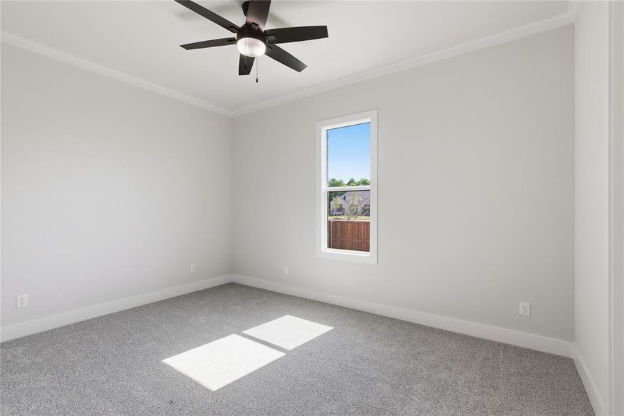Bedroom featuring light gray carpeting, neutral wall paint, a ceiling fan with integrated lighting, a single window, and white crown molding