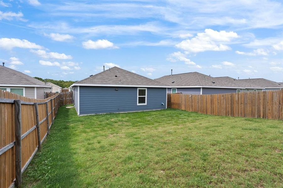 Back of property with a fenced backyard and roof with shingles