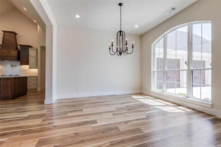 Unfurnished dining area featuring a chandelier and luxury vinyl wood-style floors