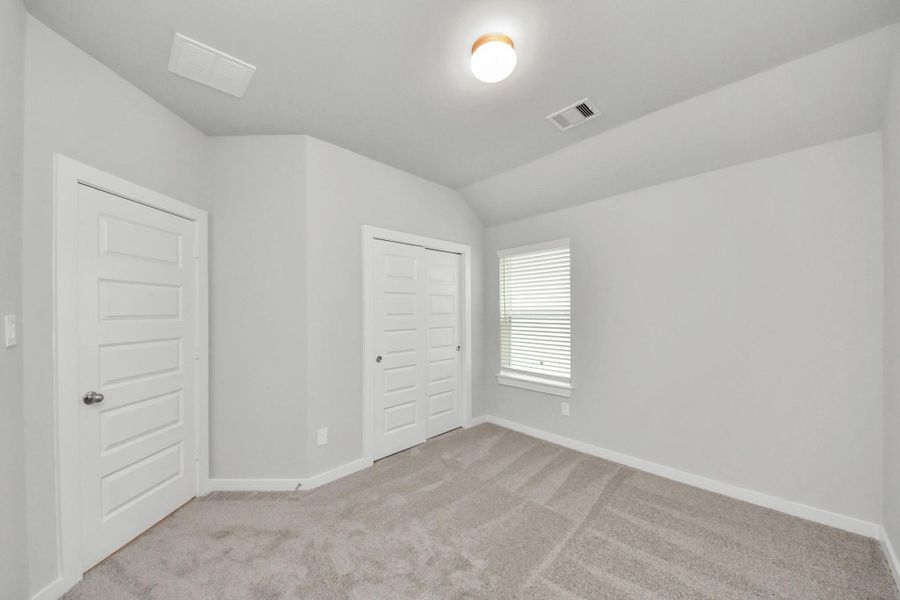 Secondary bedroom features plush carpeting, large windows that let in plenty of natural light, bright paint, and spacious closets.