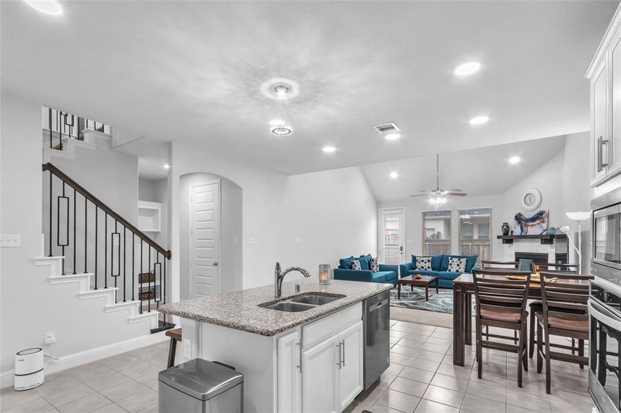 Kitchen featuring a center island with sink, stainless steel appliances, open floor plan, white cabinetry, and a sink