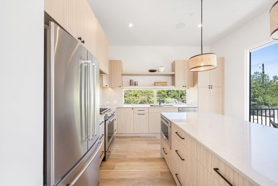 Kitchen featuring light brown cabinetry, modern cabinets, stainless steel appliances, light stone counters, and recessed lighting
