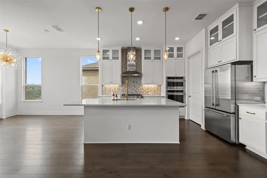 Kitchen featuring visible vents, wall chimney exhaust hood, dark wood-style flooring, and stainless steel appliances