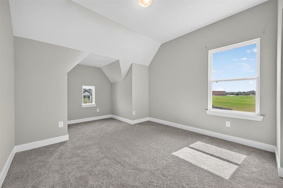 This large upstairs bedroom features distinctive lines and elevated ceiling details that add architectural interest. Large windows offer scenic views and fill the room with sunlight.