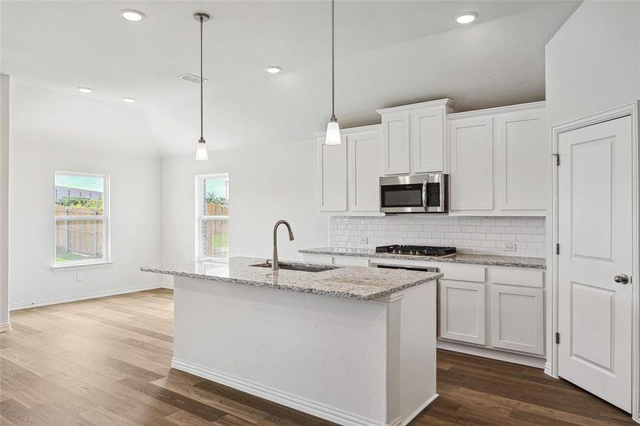 Kitchen with stainless steel appliances, backsplash, hardwood / wood-style flooring, and white cabinets