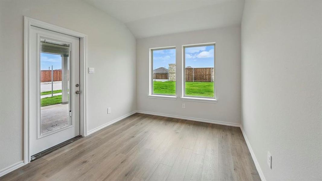 Empty room with vaulted ceiling and light wood-style flooring