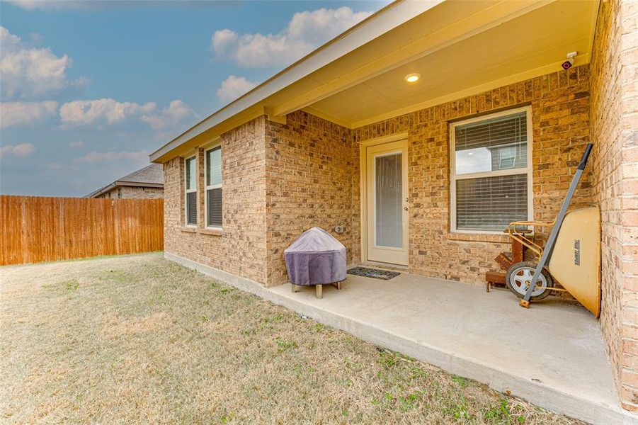 View of exterior entry with a patio area and a yard