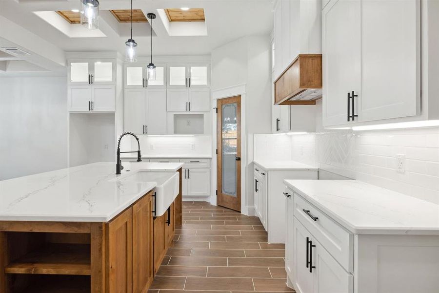 Kitchen with a skylight, light stone countertops, and white cabinets