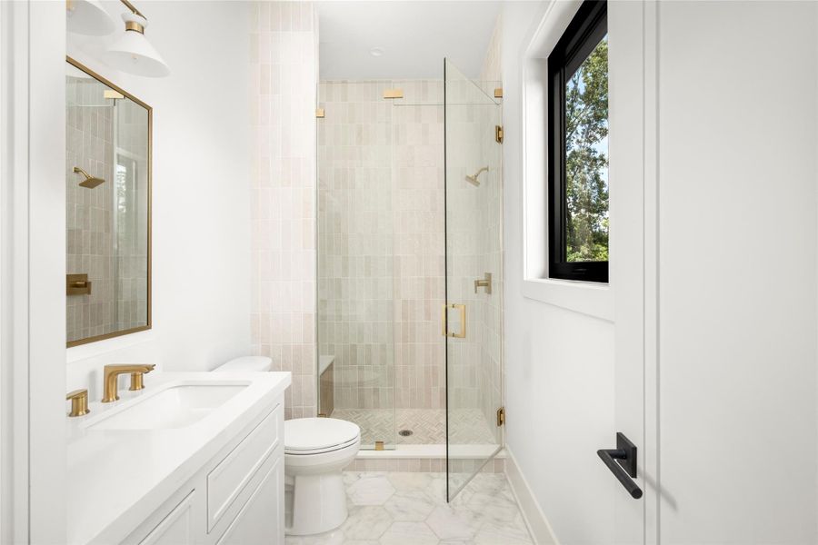 Modern bathroom with clean lines, elegant finishes, natural ight, and large walk in shower.