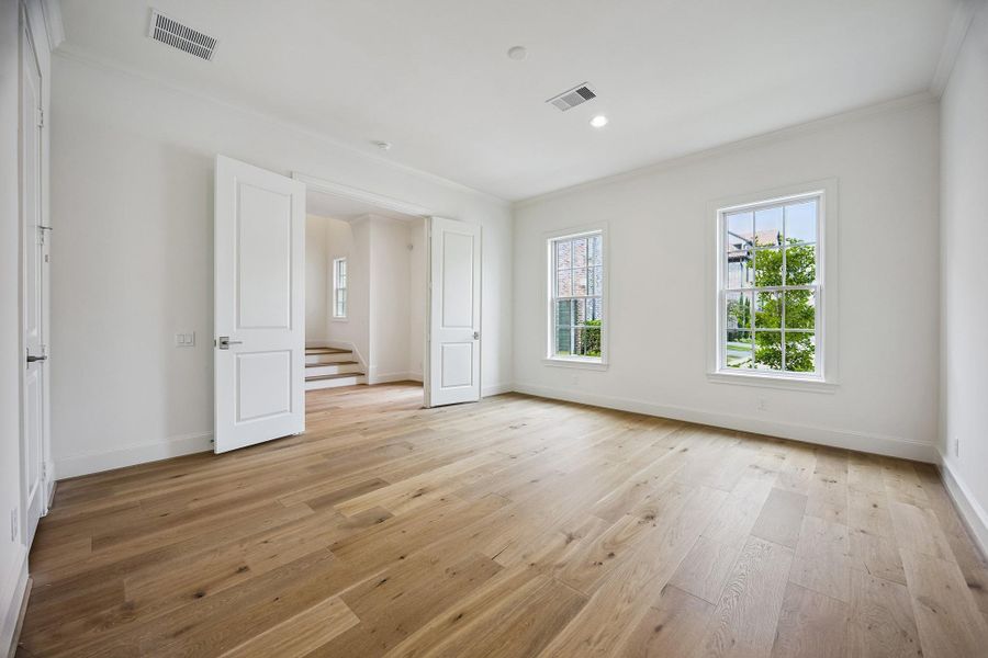 Spacious first-floor secondary bedroom with hardwood floors and abundant natural light.