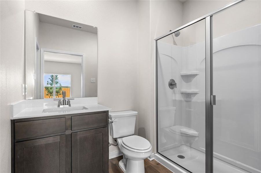 Full bathroom featuring a stall shower, vanity, and dark wood-type flooring