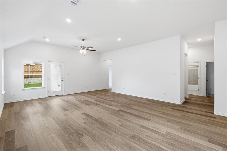 Spacious living area featuring vaulted ceilings, wood-finish flooring, recessed lighting, and a ceiling fan