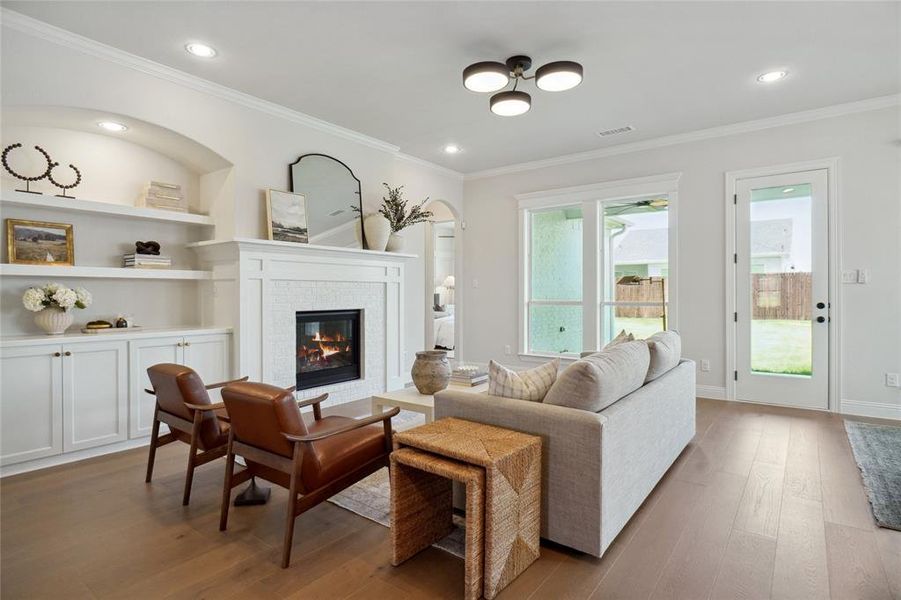 Living room featuring crown molding, light wood-type flooring, and built in shelves