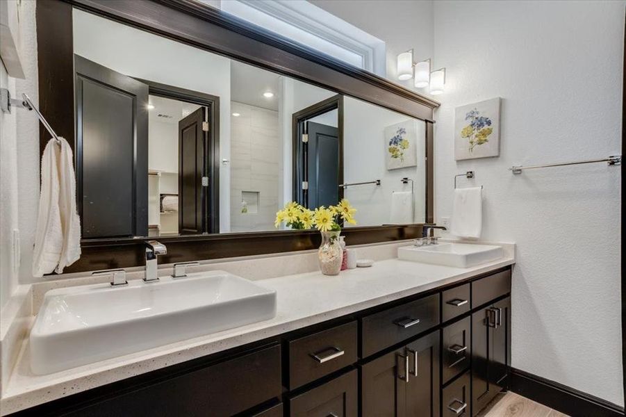 Bathroom with double vanity, a textured wall, and light tile finished floors