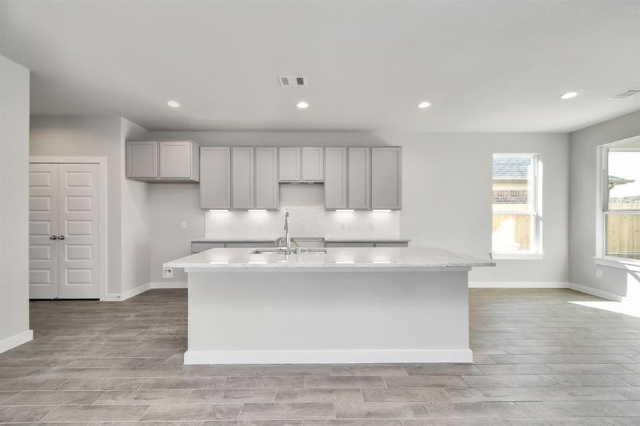 Culinary haven, featuring granite countertops, a tile backsplash, stainless steel appliances, 42” upper cabinets, and undercabinet lighting. Sample photo of completed home with similar floor plan. As-built interior colors and selections may vary.