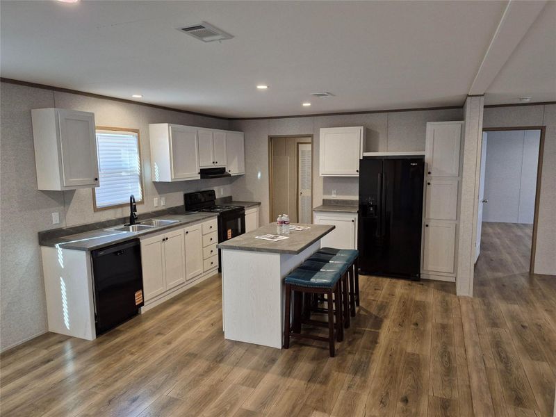 Kitchen with black appliances, white cabinetry, a kitchen bar, dark wood-style floors, and recessed lighting