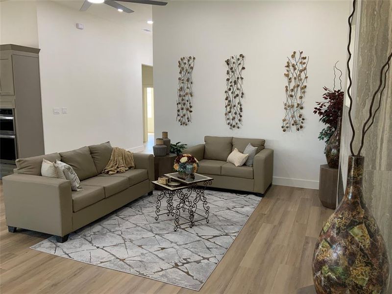 Living room featuring a high ceiling, light wood-style floors, and ceiling fan Living room featuring a high ceiling, light wood-style floors, and ceiling fan