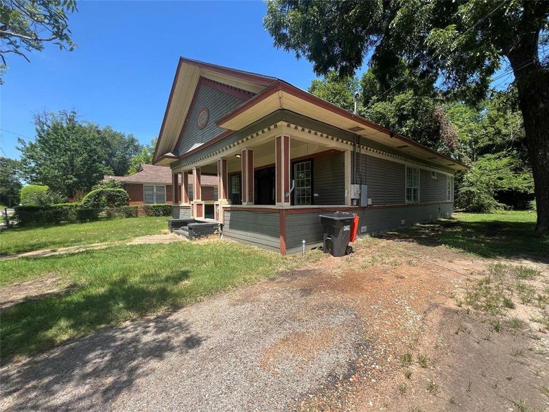 View of side of home featuring covered porch and a yard View of side of home featuring covered porch and a yard