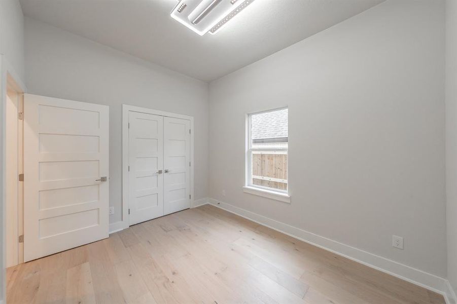 Unfurnished bedroom with light wood-type flooring, cooling unit, and a closet