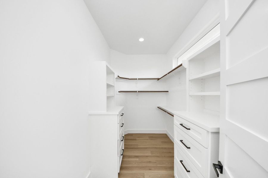 Large walk in primary closet w/ custom shelving. Large walk in primary closet w/ custom shelving.