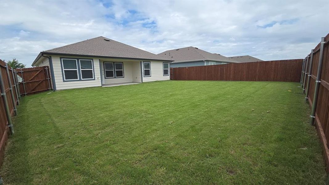 Expansive backyard featuring a manicured lawn, complete privacy fencing, and a concrete patio Expansive backyard featuring a manicured lawn, complete privacy fencing, and a concrete patio