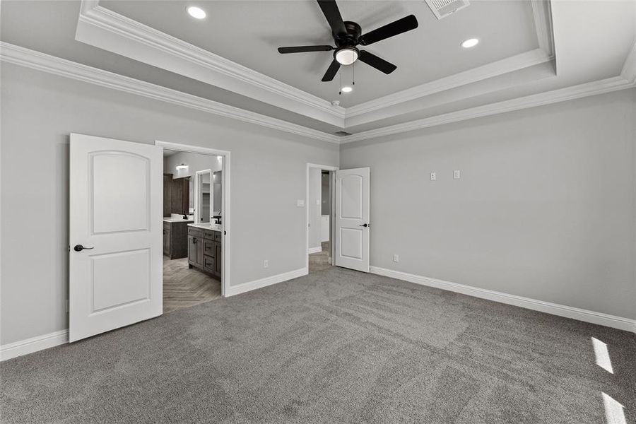 Unfurnished bedroom featuring a tray ceiling, crown molding, carpet floors, ensuite bath, and recessed lighting Unfurnished bedroom featuring a tray ceiling, crown molding, carpet floors, ensuite bath, and recessed lighting