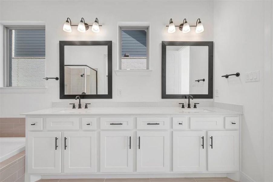 Dual vanity featuring white shaker-style cabinetry, white countertops, and matte black hardware Dual vanity featuring white shaker-style cabinetry, white countertops, and matte black hardware