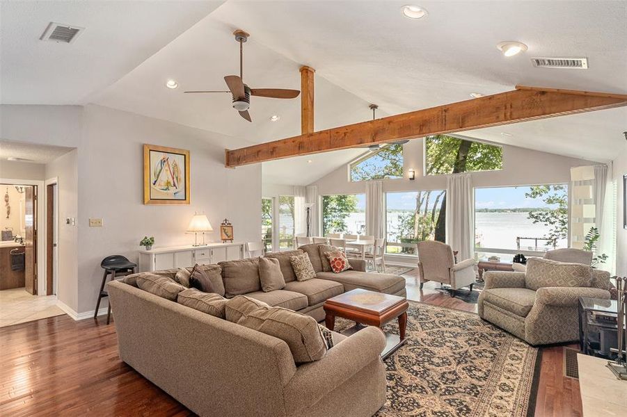 Spacious living area featuring vaulted ceilings with exposed wood beams, recessed lighting, and a ceiling fan