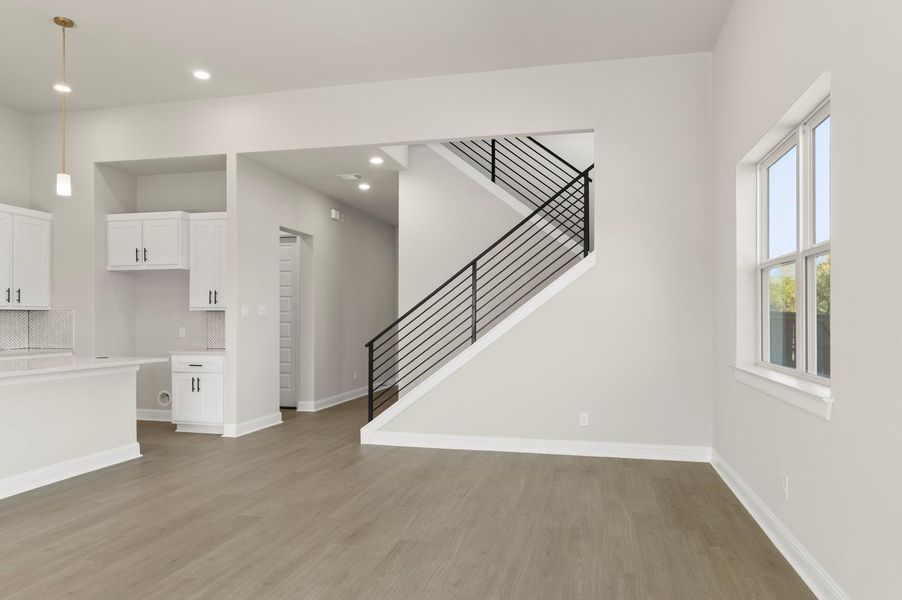 Unfurnished living room with stairs, light wood-style floors, and recessed lighting Unfurnished living room with stairs, light wood-style floors, and recessed lighting