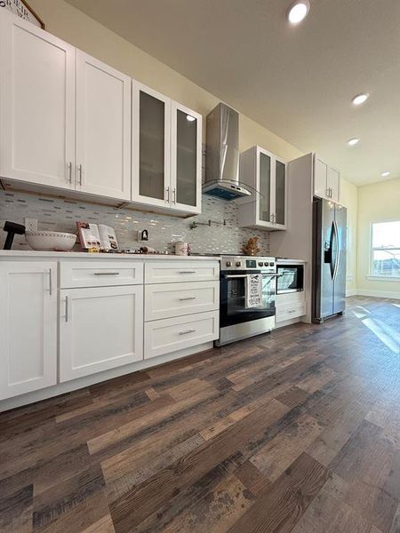 View of the the stainless pot filler, stainless steel 36" inch stove, stainless steel dishwasher, and custom backsplash.