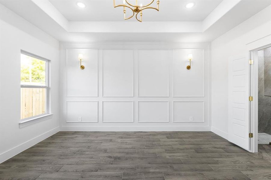 Master bedroom featuring a tray ceiling, dark hardwood / wood-style floors, and a notable chandelier