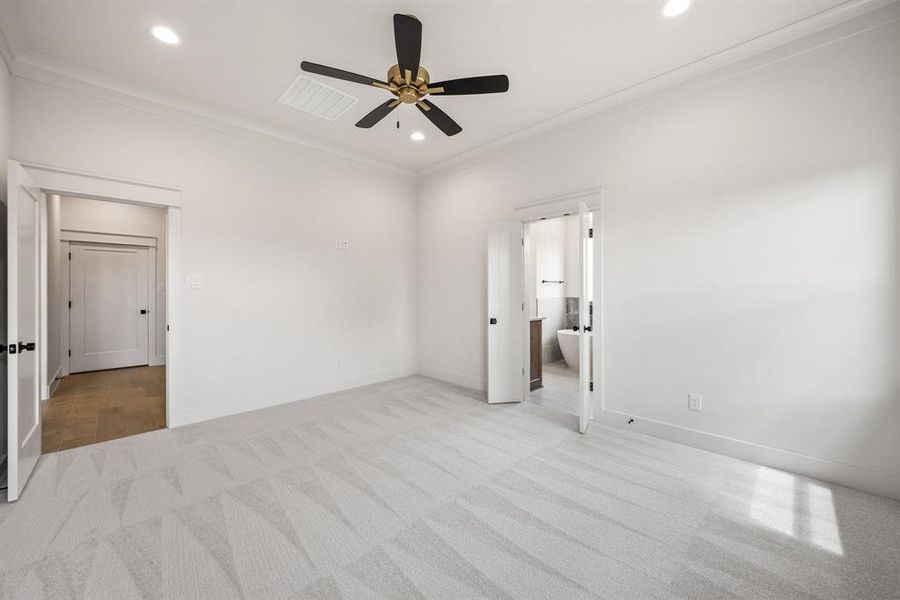 Spacious room featuring light-toned patterned carpeting, crown molding, and recessed lighting
