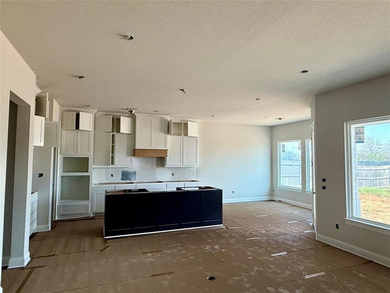 Kitchen featuring dark cabinets, white cabinetry, a center island, and a textured ceiling Kitchen featuring dark cabinets, white cabinetry, a center island, and a textured ceiling