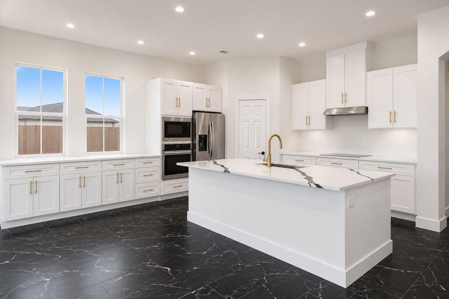 A well-lit, open-concept kitchen showcasing a large island and ample counter space.