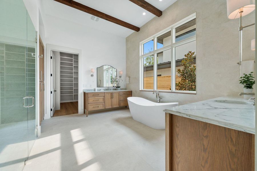 Bathroom featuring a soaking tub, beam ceiling, a stall shower, two vanities, and a spacious closet Bathroom featuring a soaking tub, beam ceiling, a stall shower, two vanities, and a spacious closet