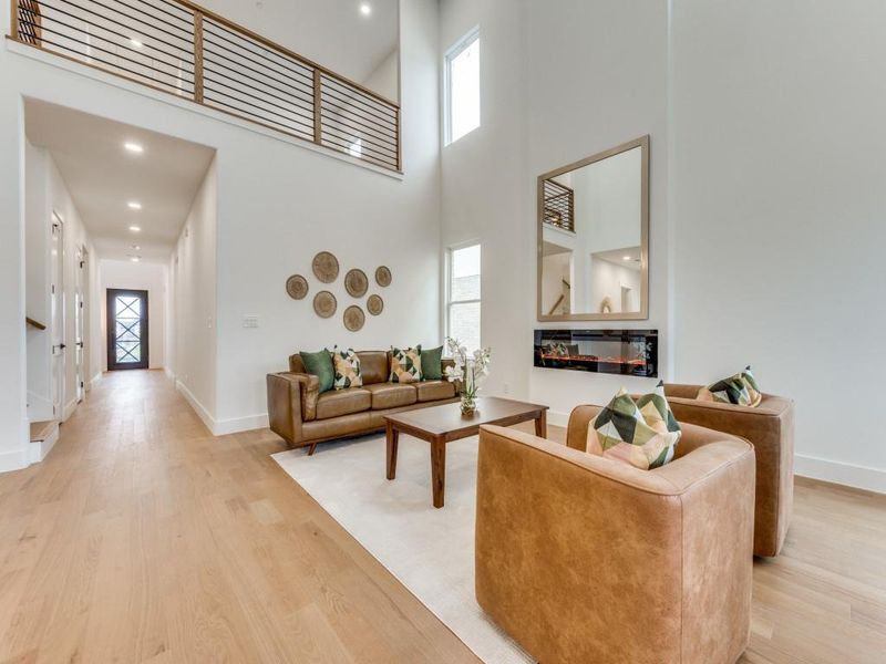 Living room with a wealth of natural light, a high ceiling, and light hardwood / wood-style flooring