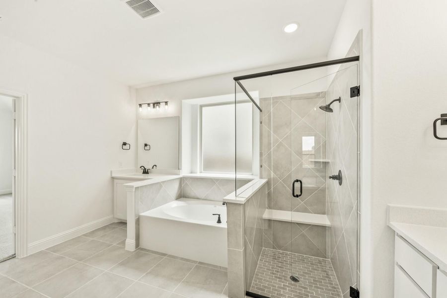 Master bathroom with soaking tub, glass walk-in shower, and tile surround with black hardware accents Master bathroom with soaking tub, glass walk-in shower, and tile surround with black hardware accents