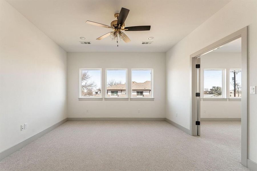 Empty room with ceiling fan and light carpet