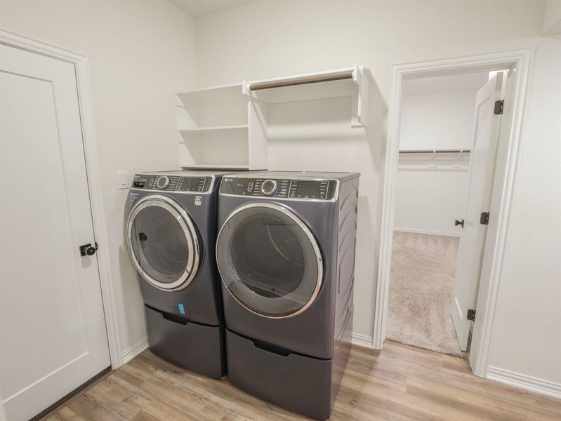 Laundry room with light wood-style flooring and ample storage