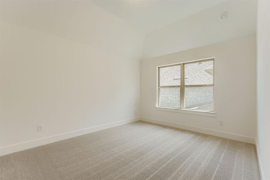 Unfurnished room featuring light carpet, lofted ceiling, and a smoke detector Unfurnished room featuring light carpet, lofted ceiling, and a smoke detector