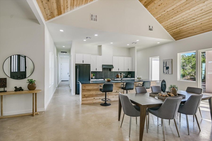 Dining space featuring high vaulted ceiling, finished concrete flooring, recessed lighting, and wooden ceiling